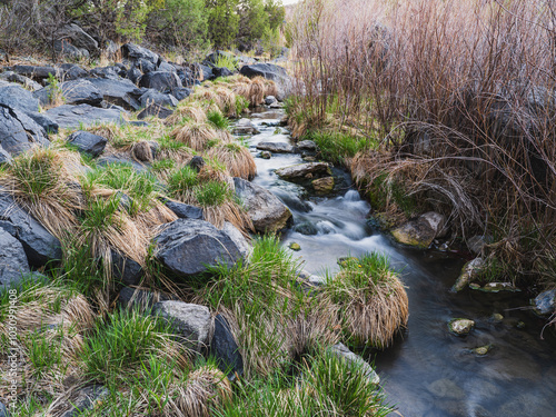 A cascading waterfall in a small canyon filled with grass and boulders in remote Northeastern New Mexico