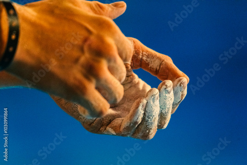 Closeup of hands applying climbing chalk with a blue evening sky behind