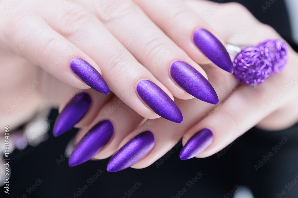 Female hand with long nails and a blue and purple color nail polish Female hand with long nails and a blue and purple color nail polish