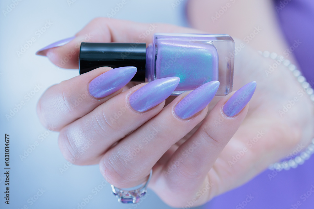 Fototapeta premium Female hand with long nails and a lilac and blue nail polish
