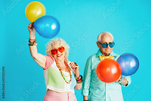 Beautiful senior old couple wearing fancy party clothes acting in studio on a colored background. Conceptual image about third age and seniority, old people feeling young inside. photo