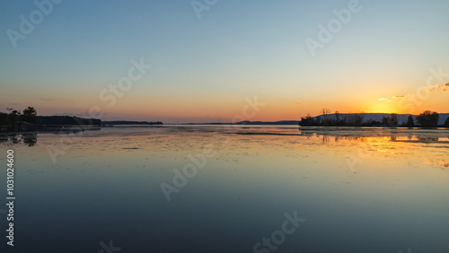wide angle sunset over a lake with the sun just below the horizon