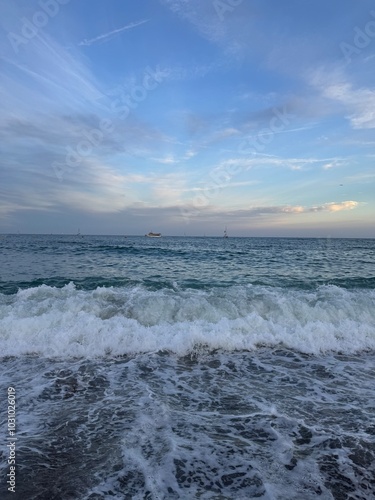 A quiet beach with gentle waves rolling onto the shore under a soft, twilight sky. The calm ocean and dim, fading light create a serene and peaceful atmosphere, ideal for unwinding and relaxation.