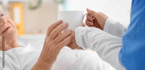 Photos Senior woman taking cup of tea from nurse in bedroom