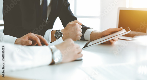 Unknown business people using tablet computer in modern office. Businessman or male entrepreneur is working with his colleague at the desk