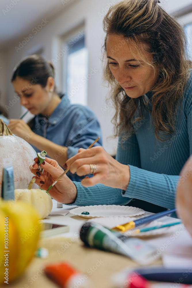 Fototapeta premium Children and adults painting pumpkins for Halloween, enjoying a fun and creative activity together.