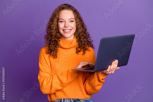 Portrait of pretty young girl hold laptop wear orange sweater isolated on purple color background photo