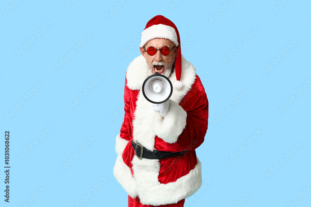 Santa Claus in sunglasses with megaphone screaming on blue background Santa Claus in sunglasses with megaphone screaming on blue background