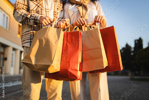 close up of man and woman hands hold colorful shopping bags outdoor photo