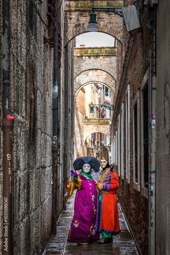 Venice, Italy - February 11, 2024: 2 masked people in narrow street at the Venice Carnival in Italy photo