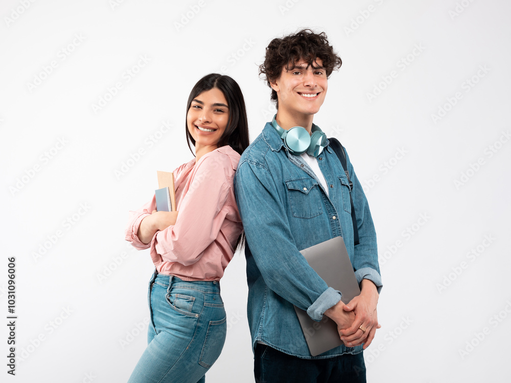 Modern Students. Happy Young Couple With Laptop And Workbooks Posing Standing Back To Back On White Studio Background, Smiling To Camera. Technology And Education, Great E-Learning Offer Concept Modern Students. Happy Young Couple With Laptop And Workbooks Posing Standing Back To Back On White Studio Background, Smiling To Camera. Technology And Education, Great E-Learning Offer Concept