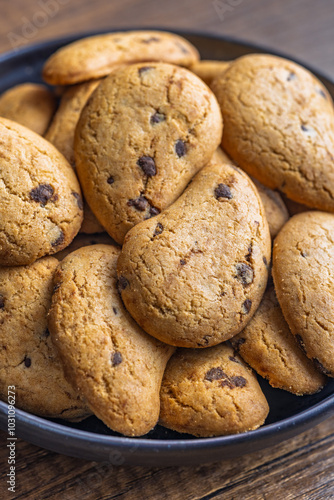 Biscotti frollini con gocce di cioccolato. Chocolate cookies on plate on wooden table.