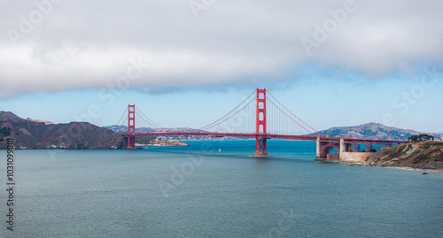 Golden Gate Bridge with Sailboat and Cloudy Sky in San Francisco Bay