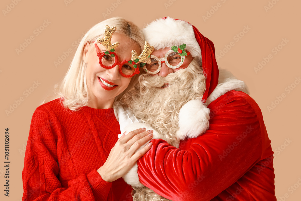 Φωτογραφία Happy Santa Claus and beautiful mature woman in Christmas glasses on brown backg