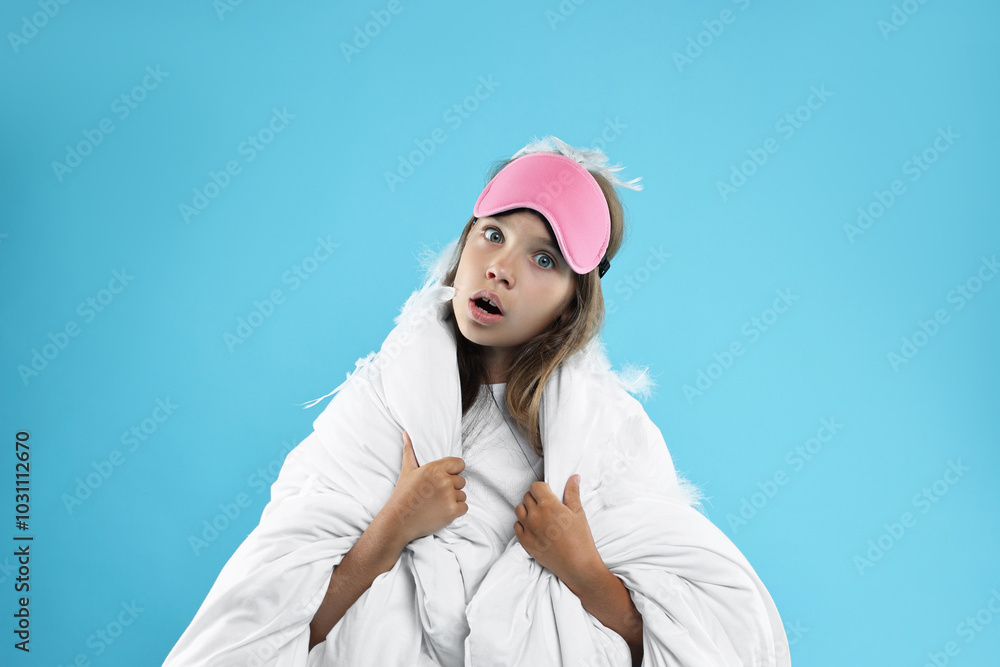 Overslept girl with sleep mask wrapped in blanket on light blue background Overslept girl with sleep mask wrapped in blanket on light blue background