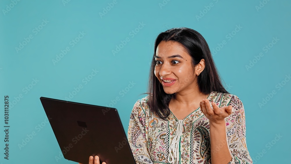 Obraz premium Upbeat woman saluting coworkers, having friendly conversations during teleconference meeting using laptop, studio background. Person discussing during online videocall on notebook device, camera B