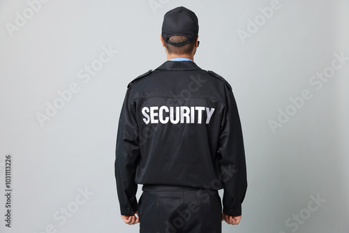 Security guard in uniform on grey background, back view