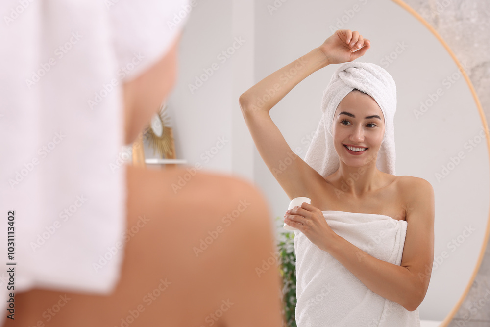 Smiling woman applying solid deodorant near mirror at home Smiling woman applying solid deodorant near mirror at home