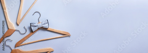 Wooden hanger with checkered bow tie surrounded by other clothes hangers. Sale banner. Selective focus, place for text