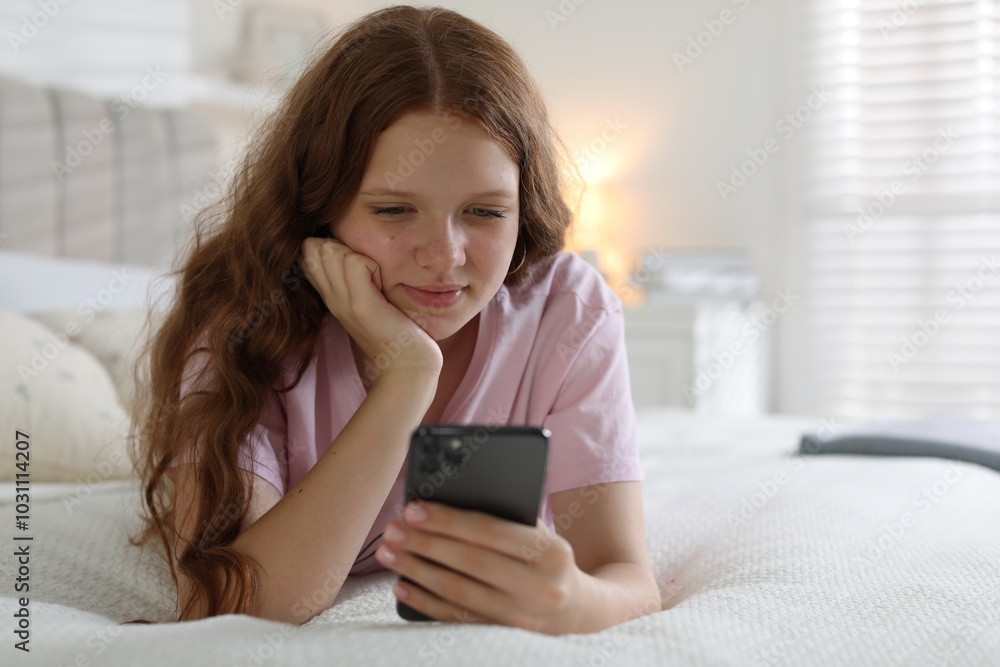 Beautiful teenage girl using smartphone on bed at home Beautiful teenage girl using smartphone on bed at home