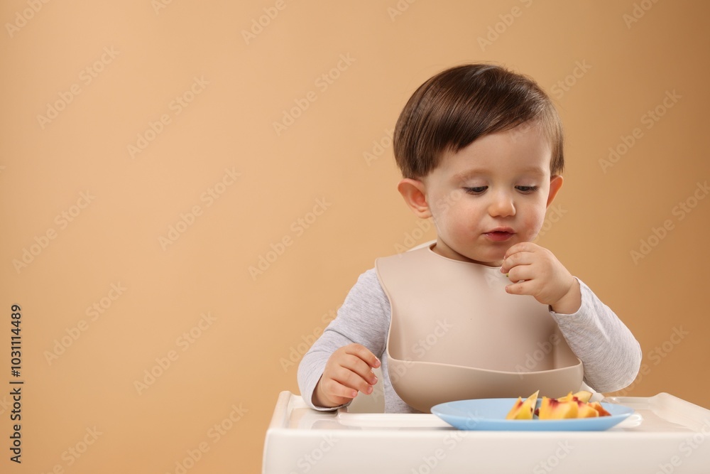 Healthy baby food. Cute little kid eating fruits in high chair on beige background, space for text Healthy baby food. Cute little kid eating fruits in high chair on beige background, space for text