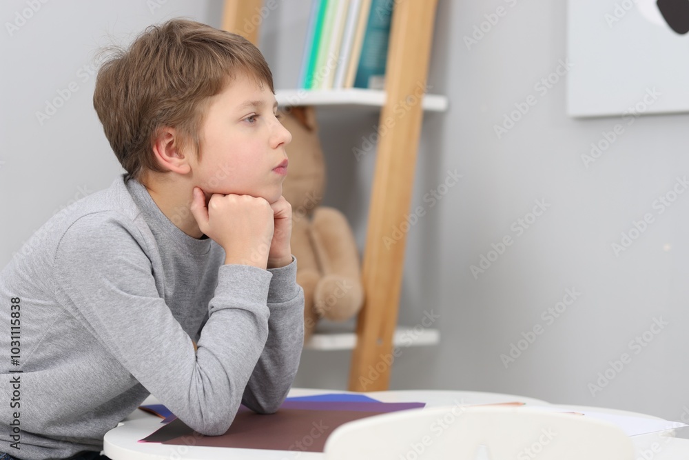 Autism concept. Lonely little boy at table indoors, space for text Autism concept. Lonely little boy at table indoors, space for text