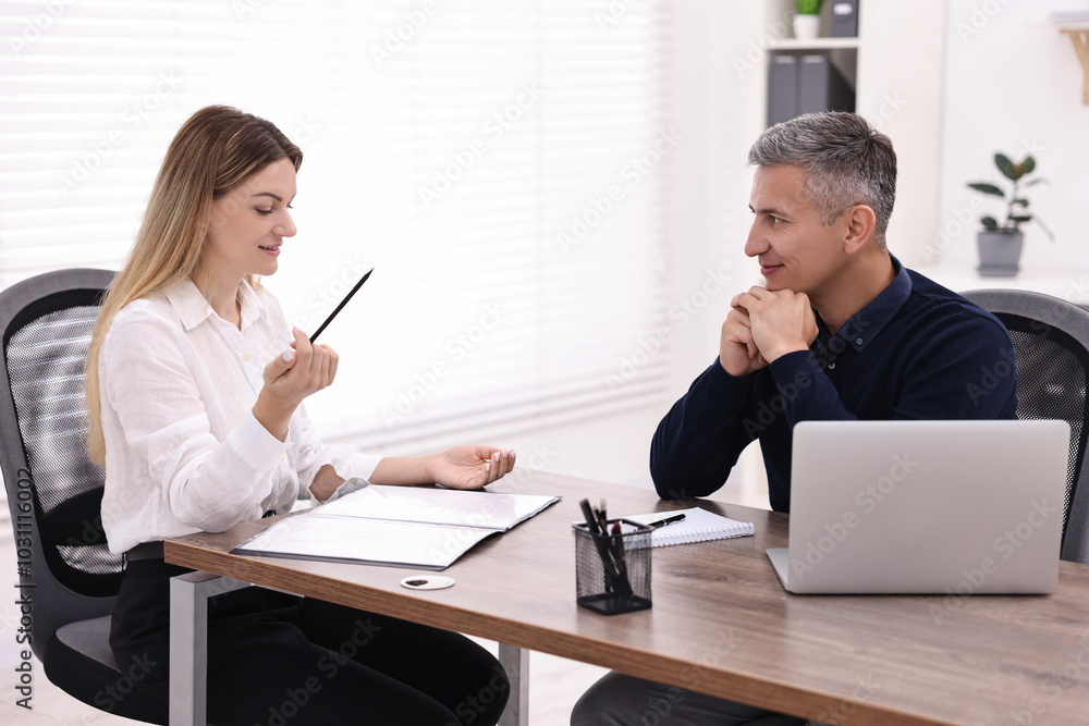 Banker working with client at wooden table in office Banker working with client at wooden table in office