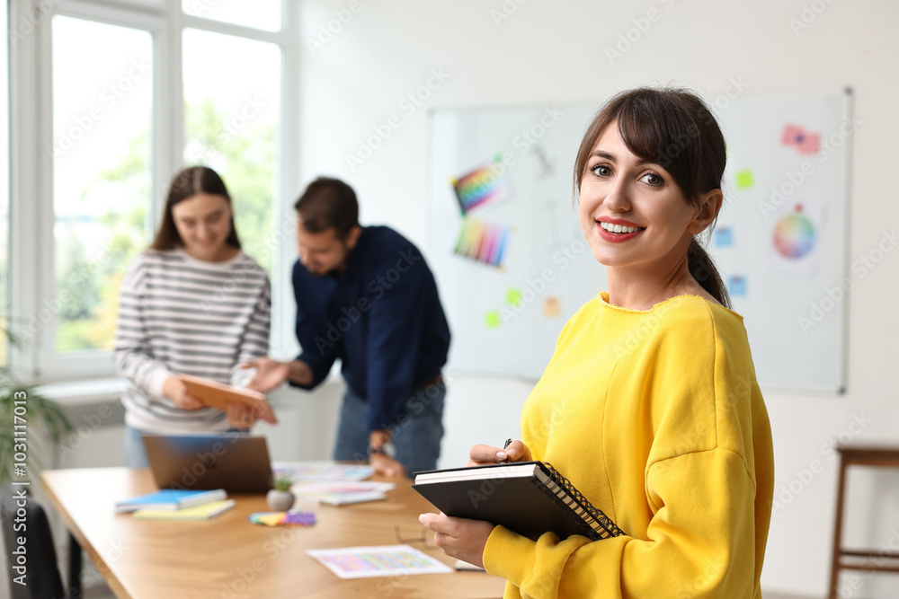 Portrait of happy young designer with notebook in office Portrait of happy young designer with notebook in office