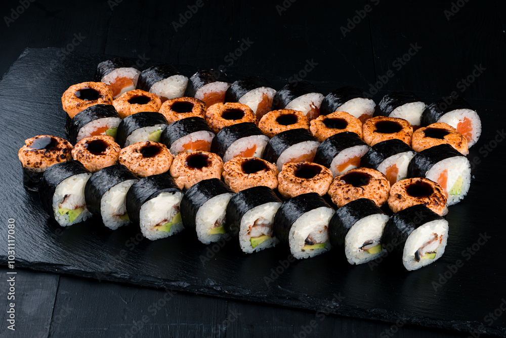 Set of maki sushi rolls with tuna, salmon, sea bass, cream cheese, avocado and teriyaki sauce.