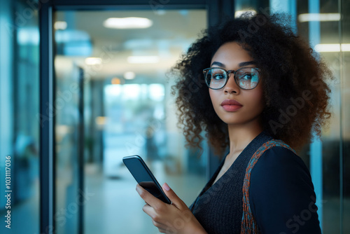 Young Businesswoman Holding Smartphone in Modern Office Environment.