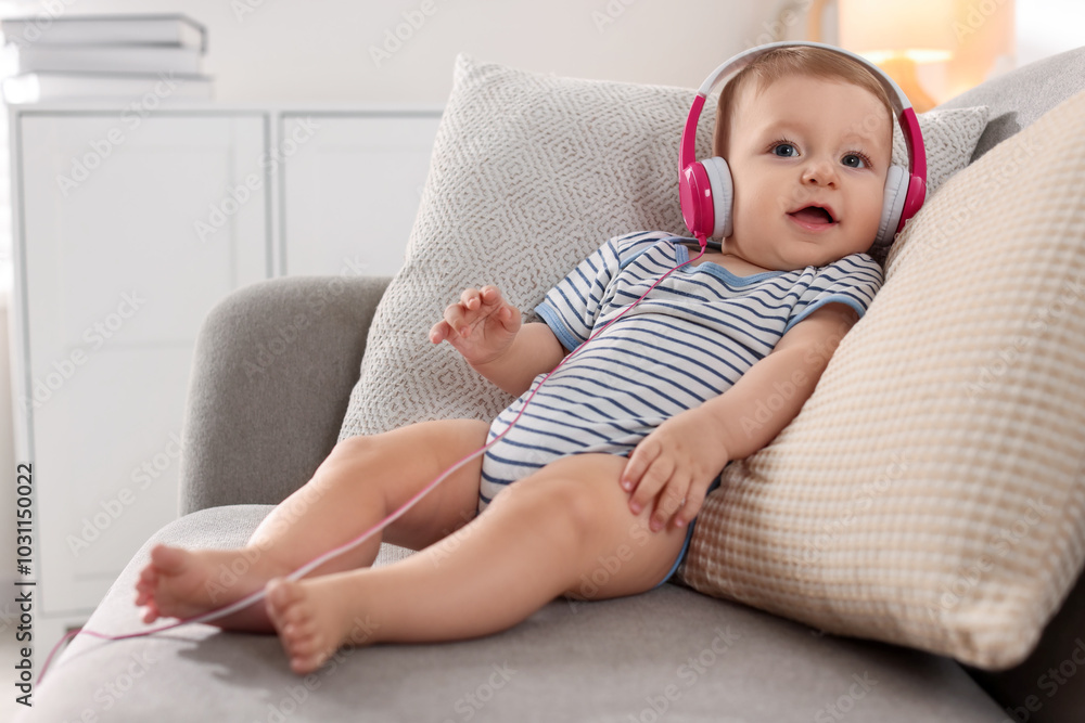 Cute little baby with headphones on sofa at home Cute little baby with headphones on sofa at home