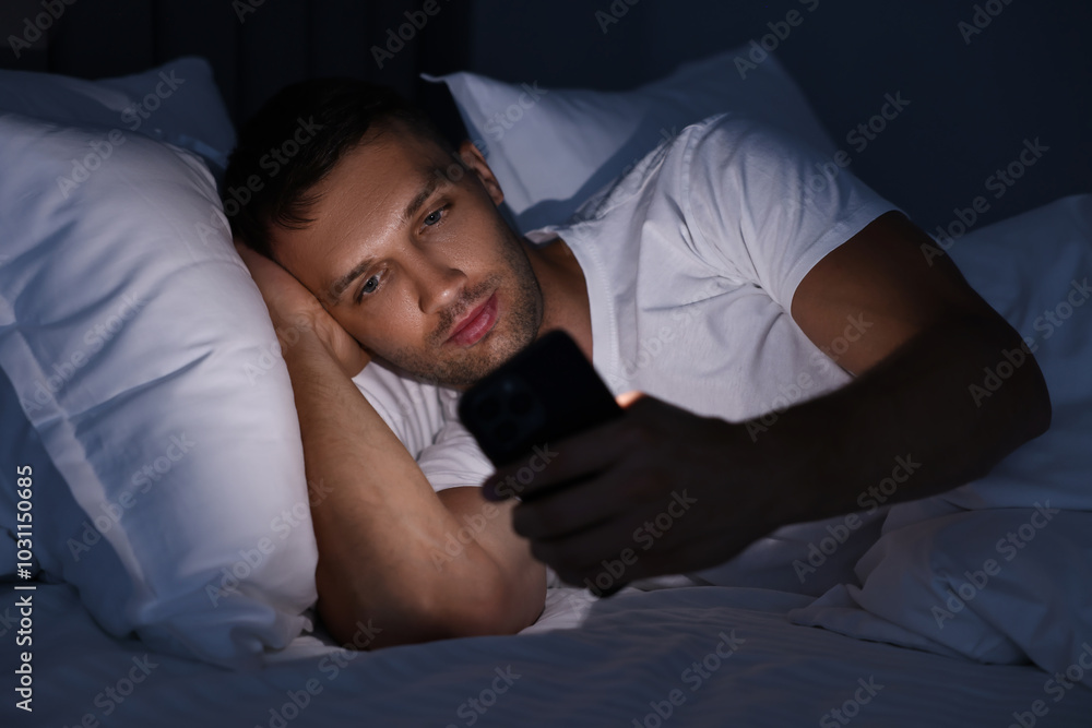 Bad habit. Man using smartphone in bed at night Bad habit. Man using smartphone in bed at night