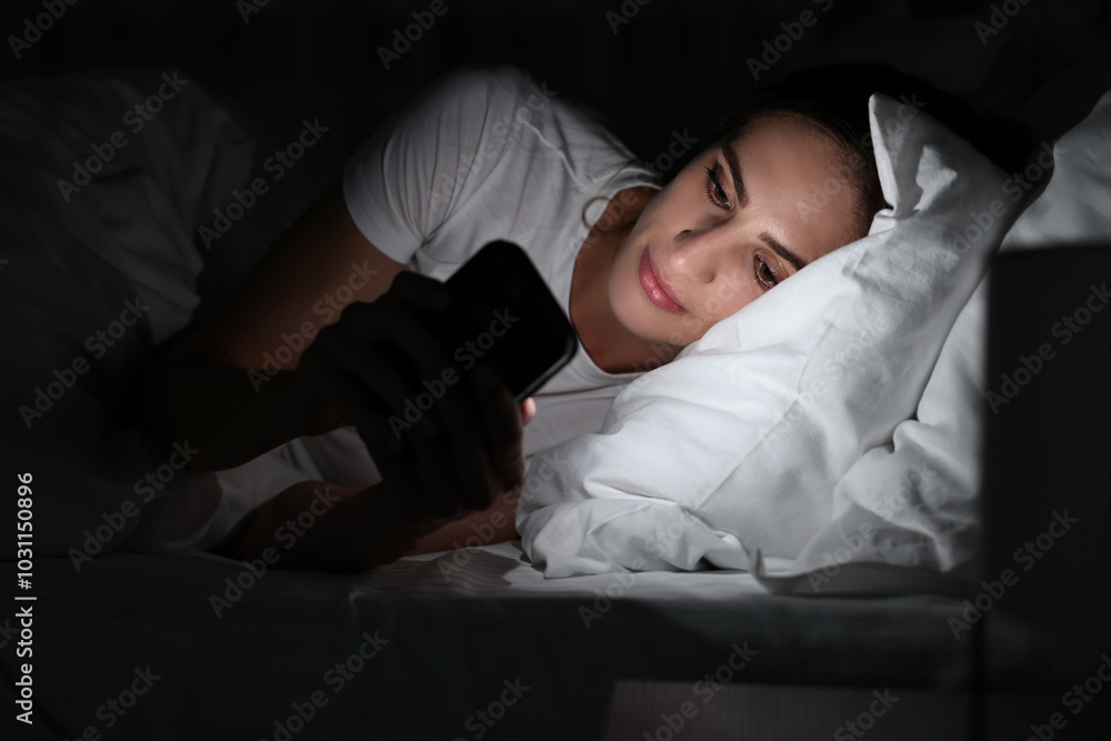 Bad habit. Young woman using smartphone in bed at night Bad habit. Young woman using smartphone in bed at night