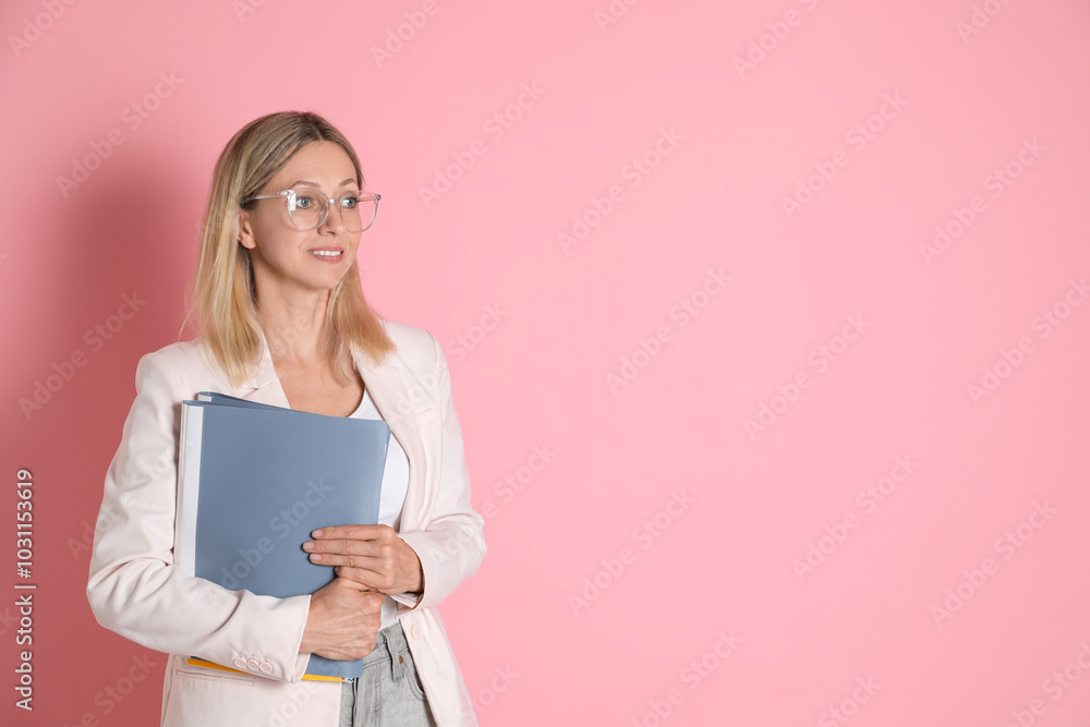 Beautiful smiling woman in glasses with folders on pink background, space for text Beautiful smiling woman in glasses with folders on pink background, space for text