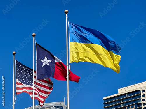 American, Texas and Ukraine Flag blowing in the wind against a deep blue sky and buildings in the background