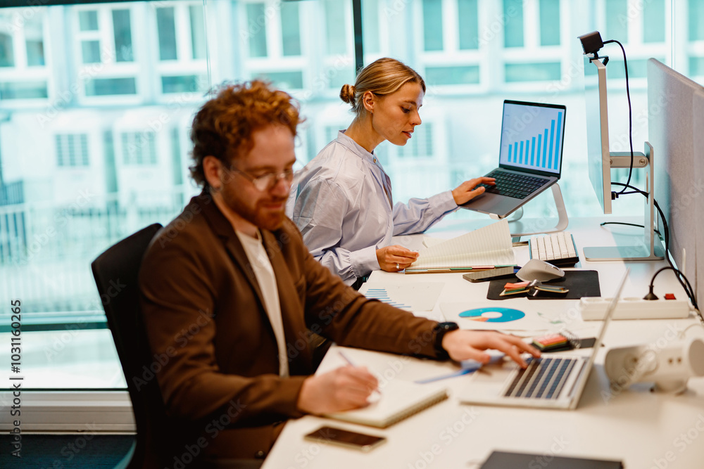 Professionals are collaborating in a brightly lit office space while analyzing data on their laptops and devices Professionals are collaborating in a brightly lit office space while analyzing data on their laptops and devices