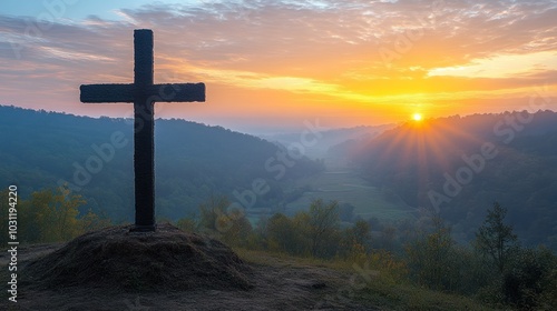 Cross silhouetted against a sunrise over a misty valley.