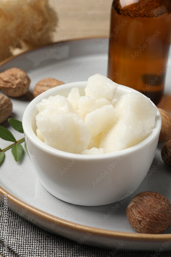 Shea butter in bowl and nuts on table, closeup Shea butter in bowl and nuts on table, closeup