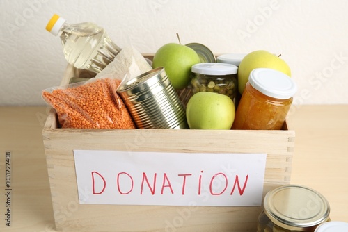 Obraz na plátně Different donation food products in crate on wooden table, closeup