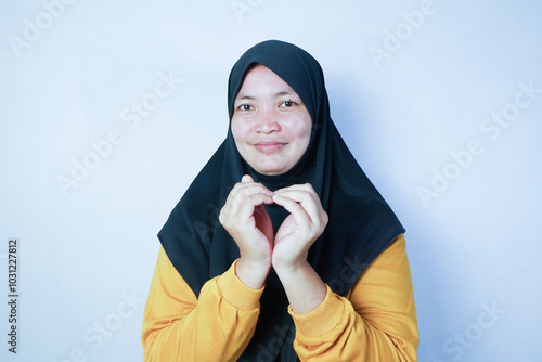 Muslim woman with smile forming love sign with hands. white background