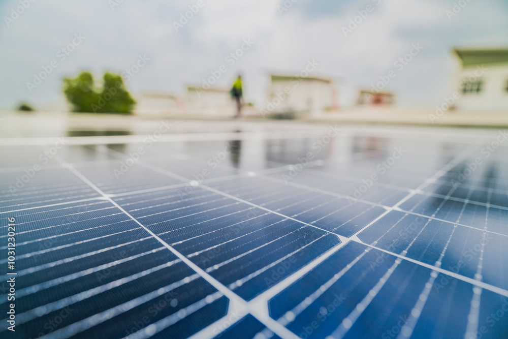 Fototapeta premium A close up of solar panels with a worker blurred in the background. The focus on the panels emphasizes the importance of renewable energy technology and solar power installations.