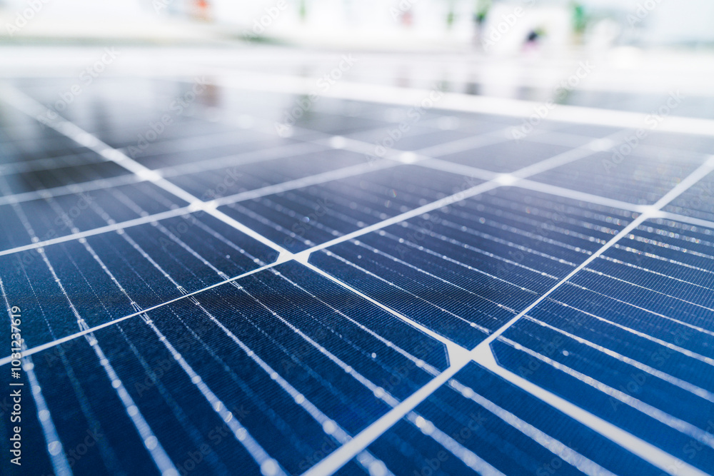 A close up of solar panels with a worker blurred in the background. The focus on the panels emphasizes the importance of renewable energy technology and solar power installations. A close up of solar panels with a worker blurred in the background. The focus on the panels emphasizes the importance of renewable energy technology and solar power installations.