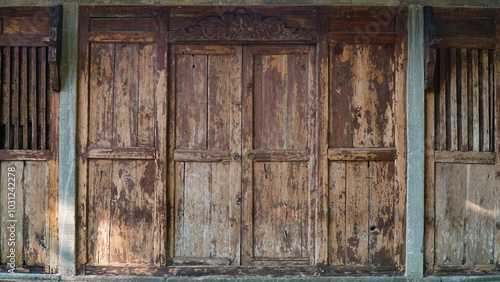 The walls of the house are made of wood. There are doors and windows. It looks old and vintage.
