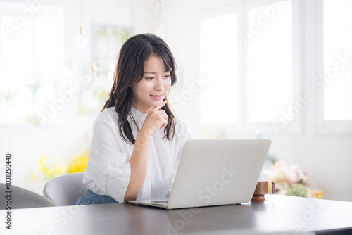 Young woman smiling and worried while looking at computer Image of a young pretty woman changing jobs, studying, etc.