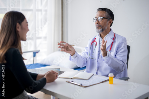 Senior doctor explaining diagnosis to young female patient in hospital room