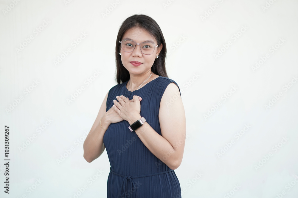 Beautiful Asian woman gently places her hand on her chest, expressing a self-love gesture on a white background Beautiful Asian woman gently places her hand on her chest, expressing a self-love gesture on a white background