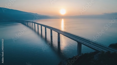 A long bridge stretches across the water towards the setting sun, creating a breathtaking silhouette against the horizon.