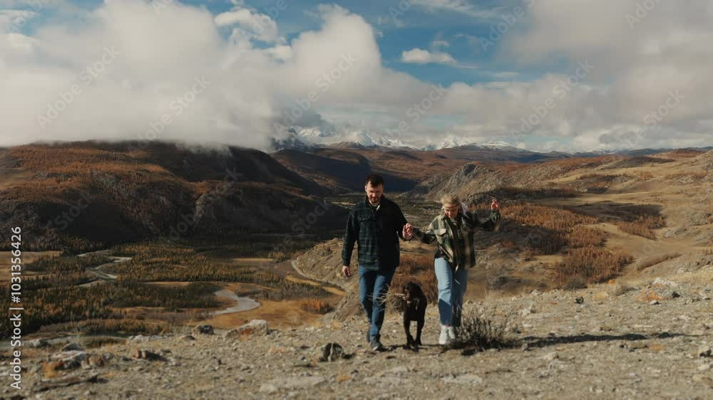 A couple of tourists, a woman and a man and a dog, are traveling in the mountains, the couple holds hands and walks forward up the mountain. Travel and mountain tourism concept. Hiking in the wild. A couple of tourists, a woman and a man and a dog, are traveling in the mountains, the couple holds hands and walks forward up the mountain. Travel and mountain tourism concept. Hiking in the wild.