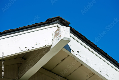 Tablou pe pânză Roof eaves with chipped and peeling white paint, revealing wear and tear against