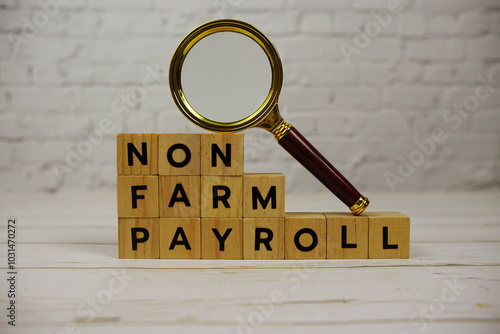 Non Farm Payroll with wooden blocks alphabet letters and magnifying glass on wooden background photo